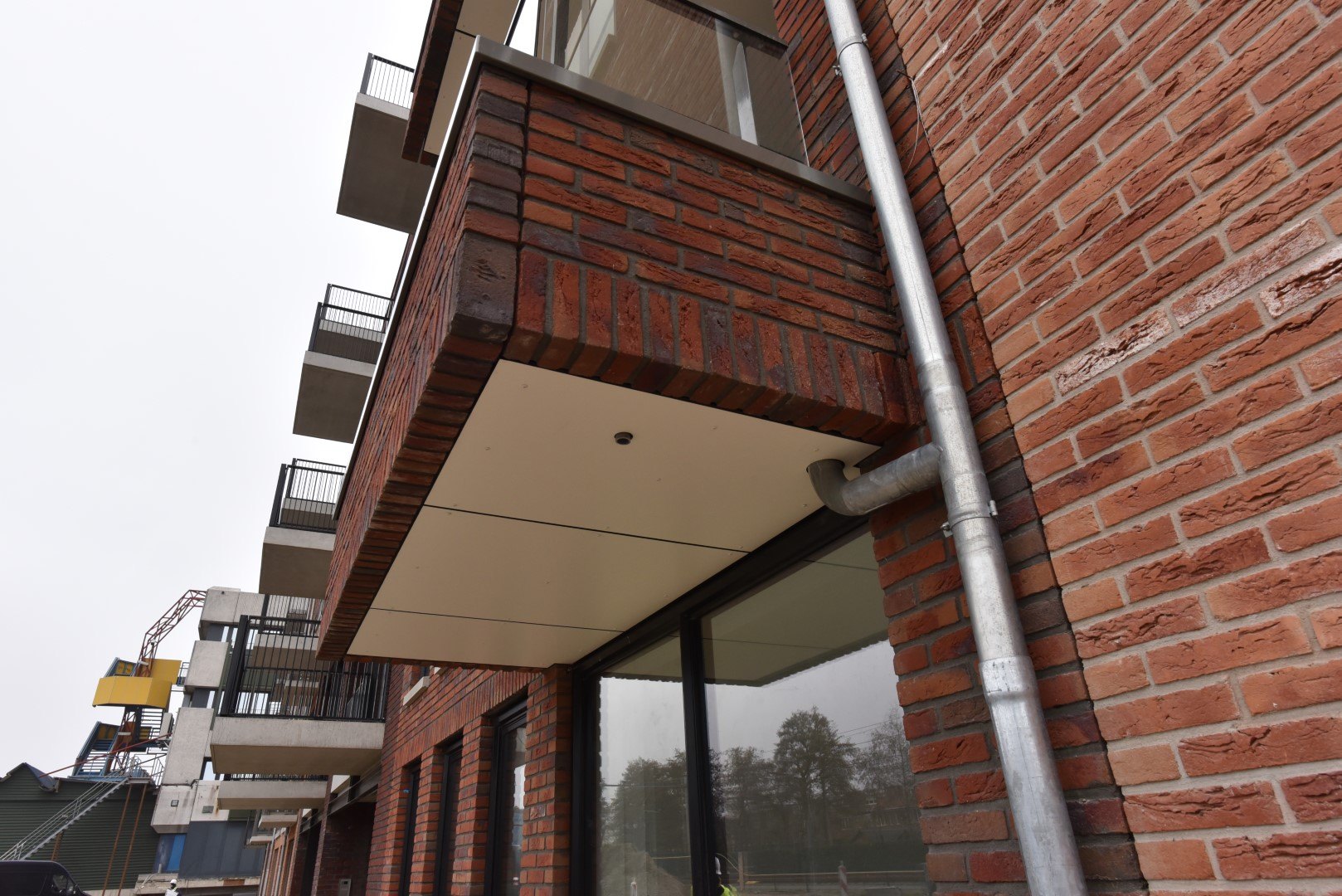 Detail van een balkonplafond in Trespa bij de rode baksteen