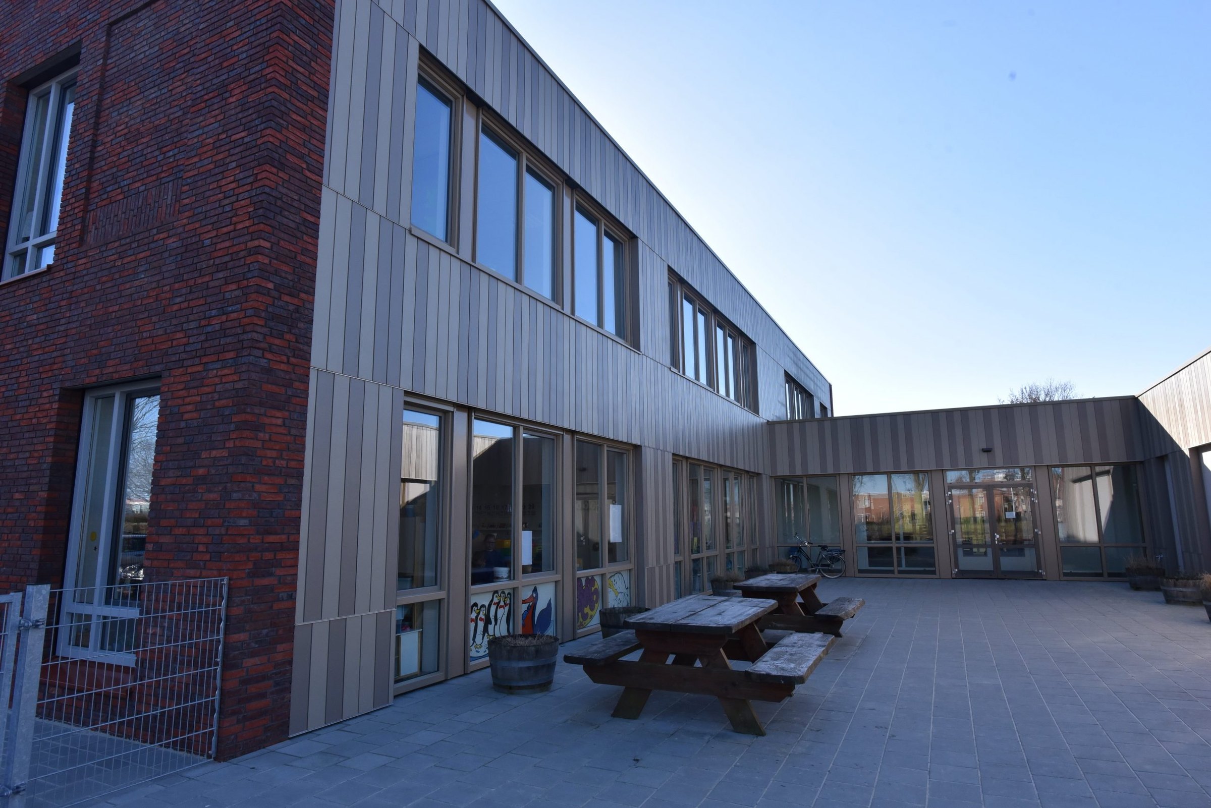 Binnenplaats van de Brede School in Scheemda met verticale Cedral Click Smooth in twee kleuren naast rode baksteen